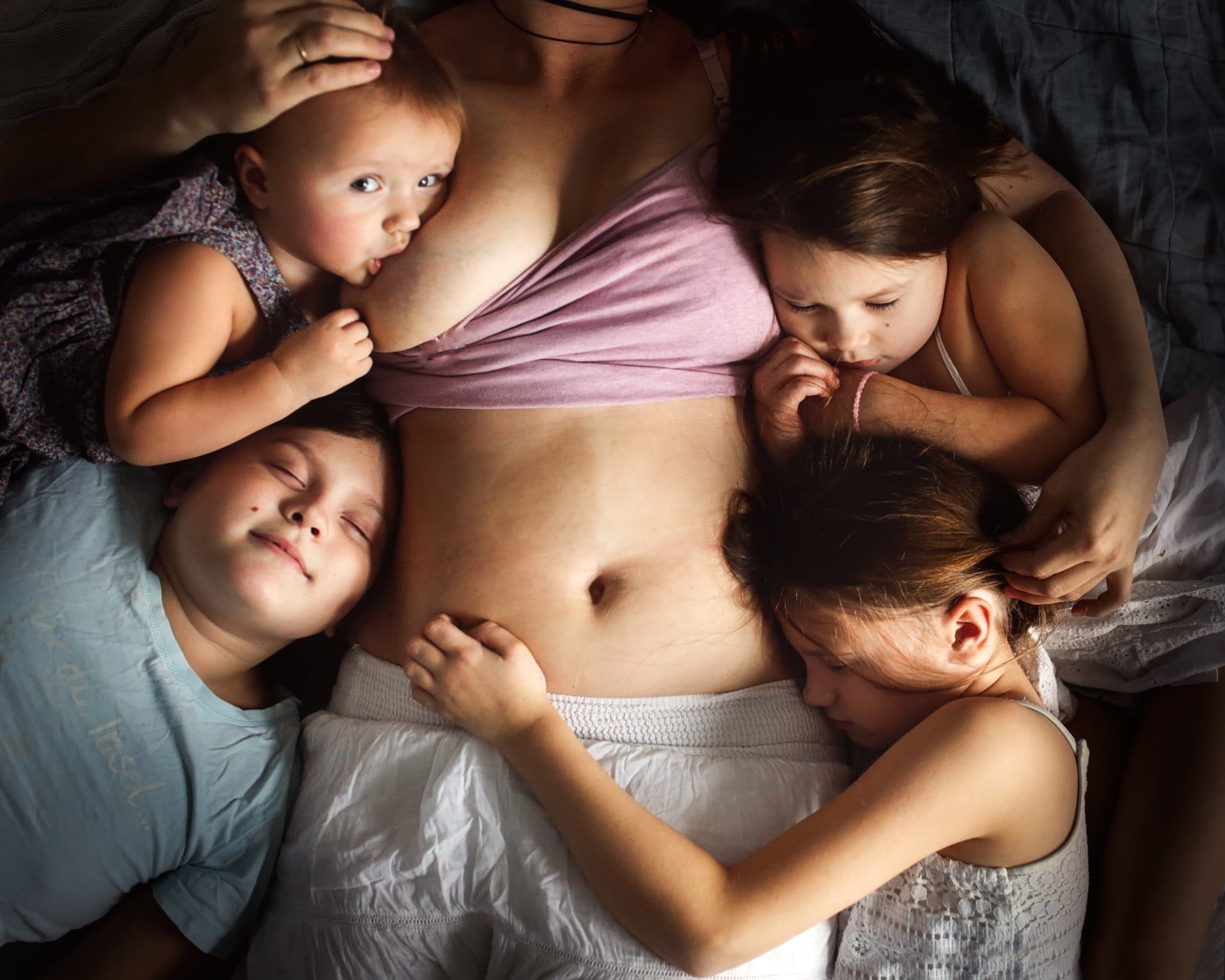 Why am I not losing weight when I breastfeed? mom breastfeeding a baby while holding three other children