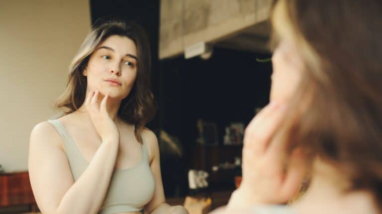Can you breastfeed with breast implants? woman looking in mirror contemplating breastfeeding after breast implants