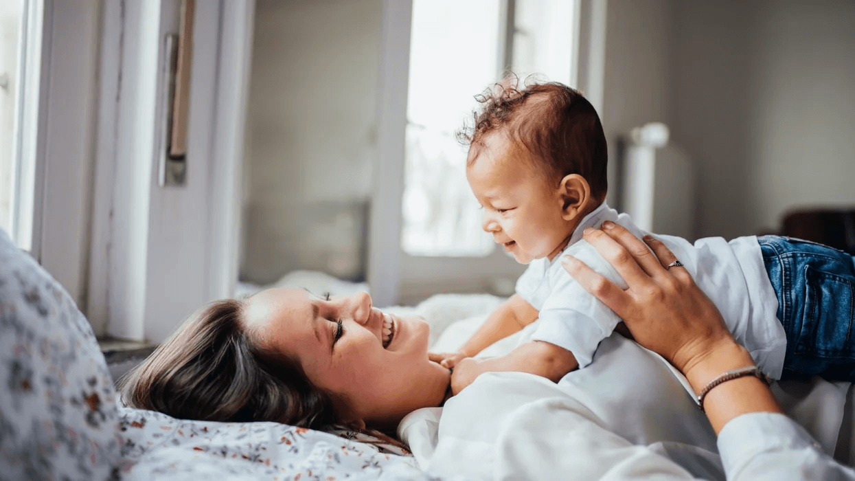 What are the best ways to stimulate baby brain development? mom lying on her back, holding her infant on her stomach, learning how to stimulate baby brain development