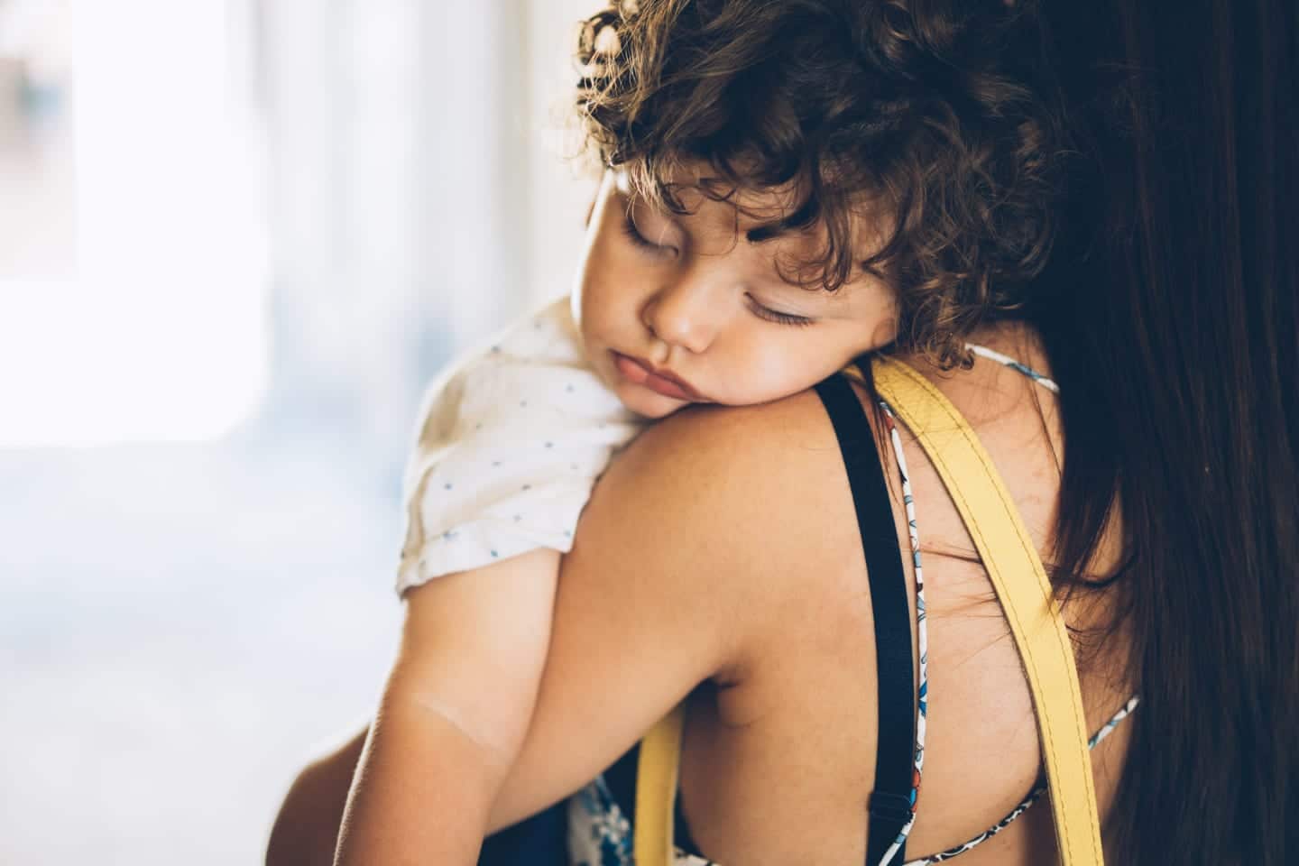 Helping your toddler transition from two naps to one mom holding a sleeping toddler - two naps to one