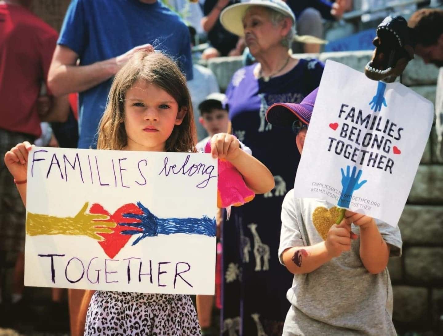 7 powerful photos moms posted during #familiesbelongtogether rallies child holding a poster