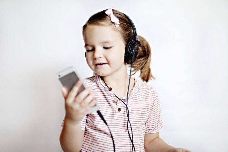 16 entertaining podcasts that will reduce your kids’ screen time child wearing headphone, listening and looking at her phone