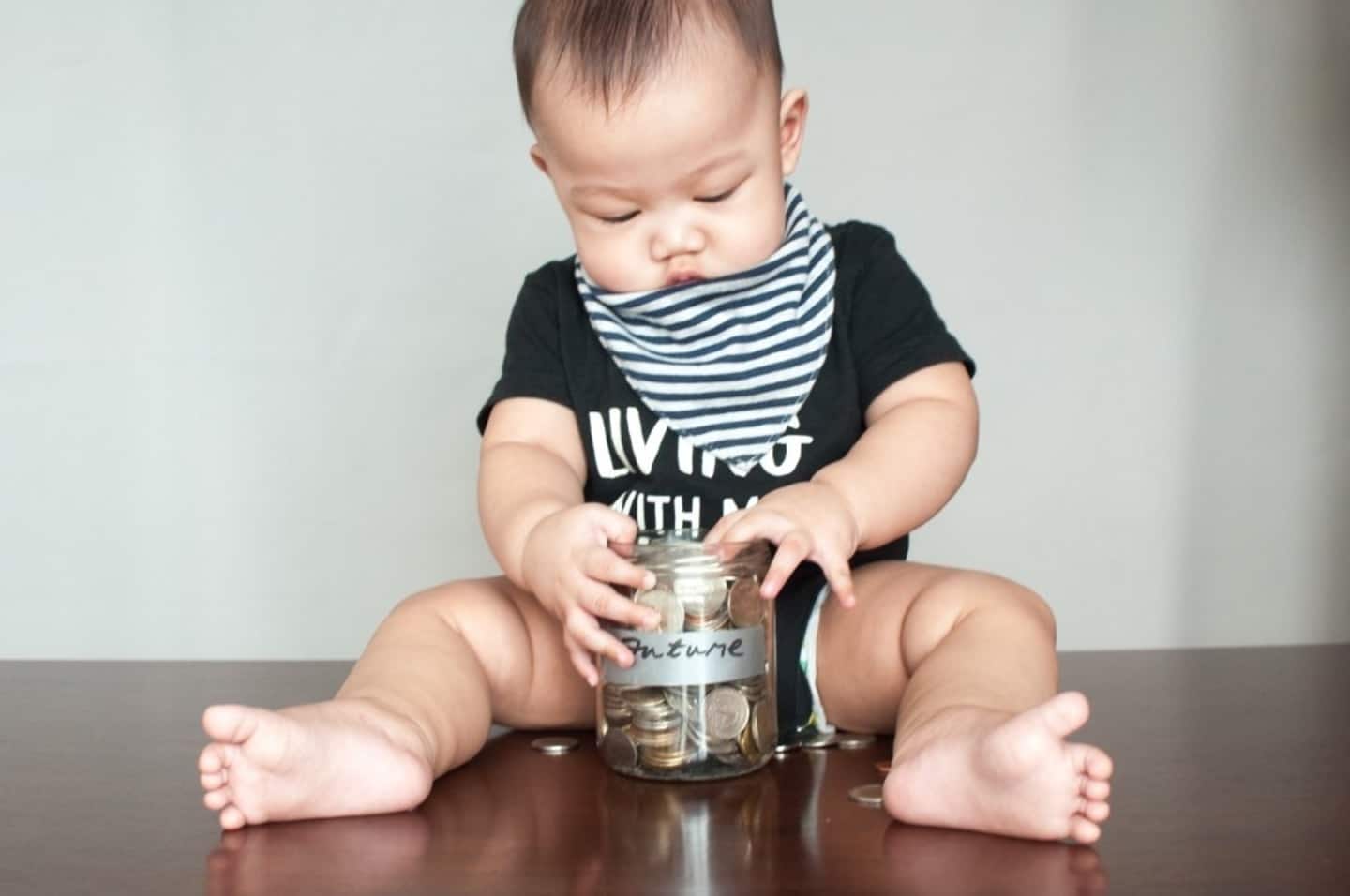 An age-by-age guide to teaching your kids about the value of money baby holding a jar full of coins