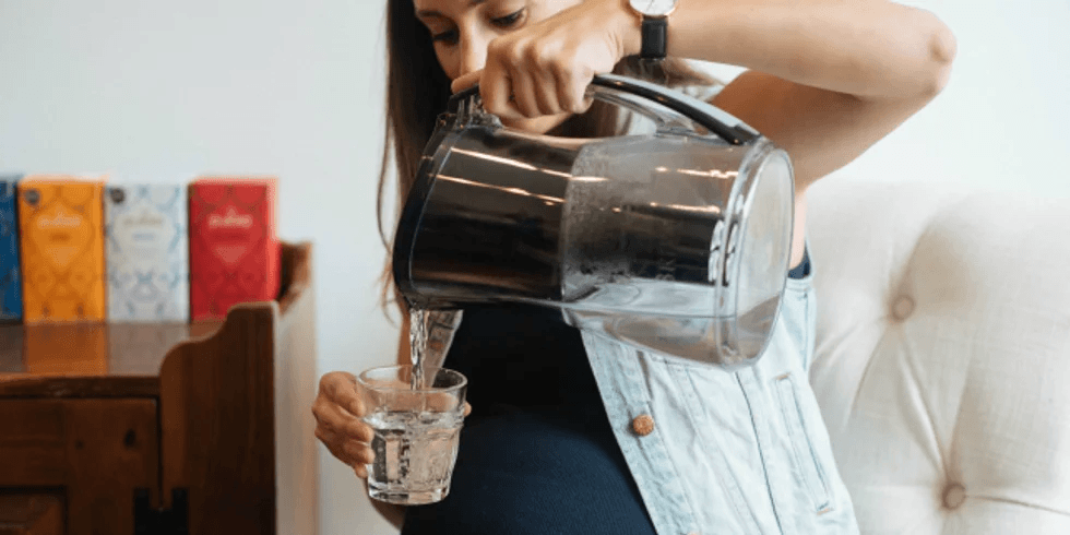 5 dangers of pregnancy dehydration pregnant woman pouring herself a glass of water