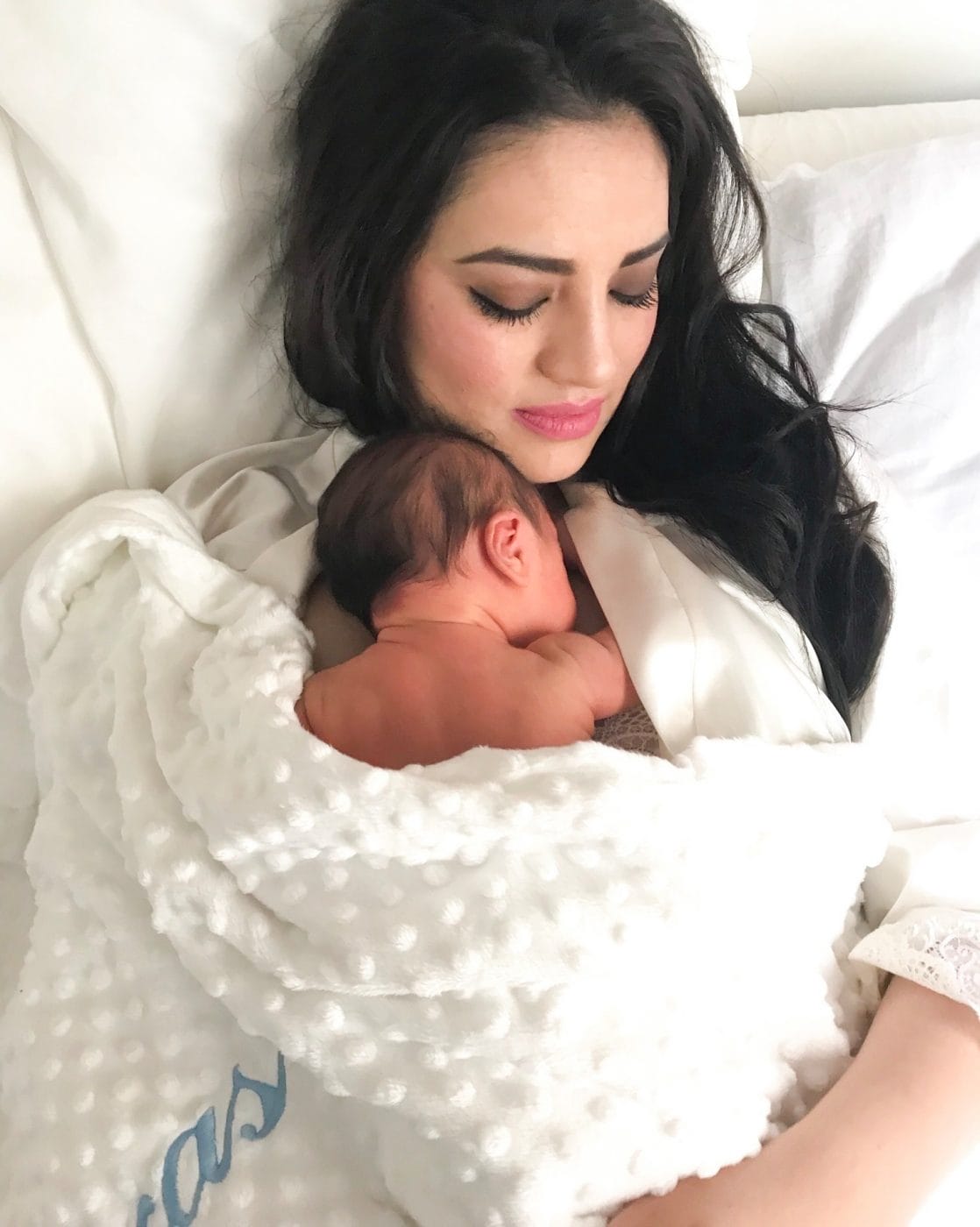 To the mother who feels lonely right now—it won’t be like this forever mom snuggling with baby on the bed wrapped in a blanket- motherhood is lonely