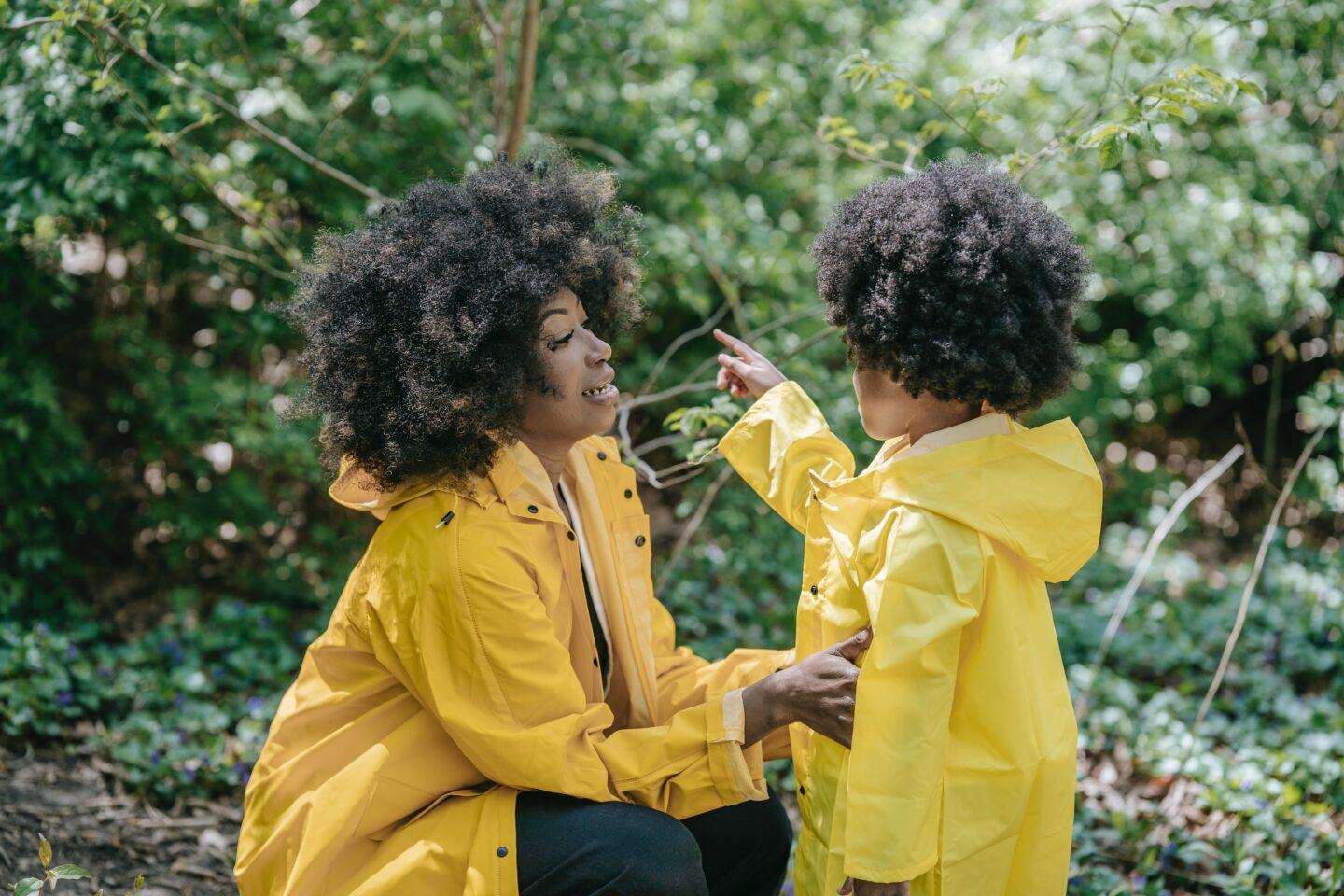 Motherhood is: Answering about 300 questions a day mom talking to child in yellow rain coat