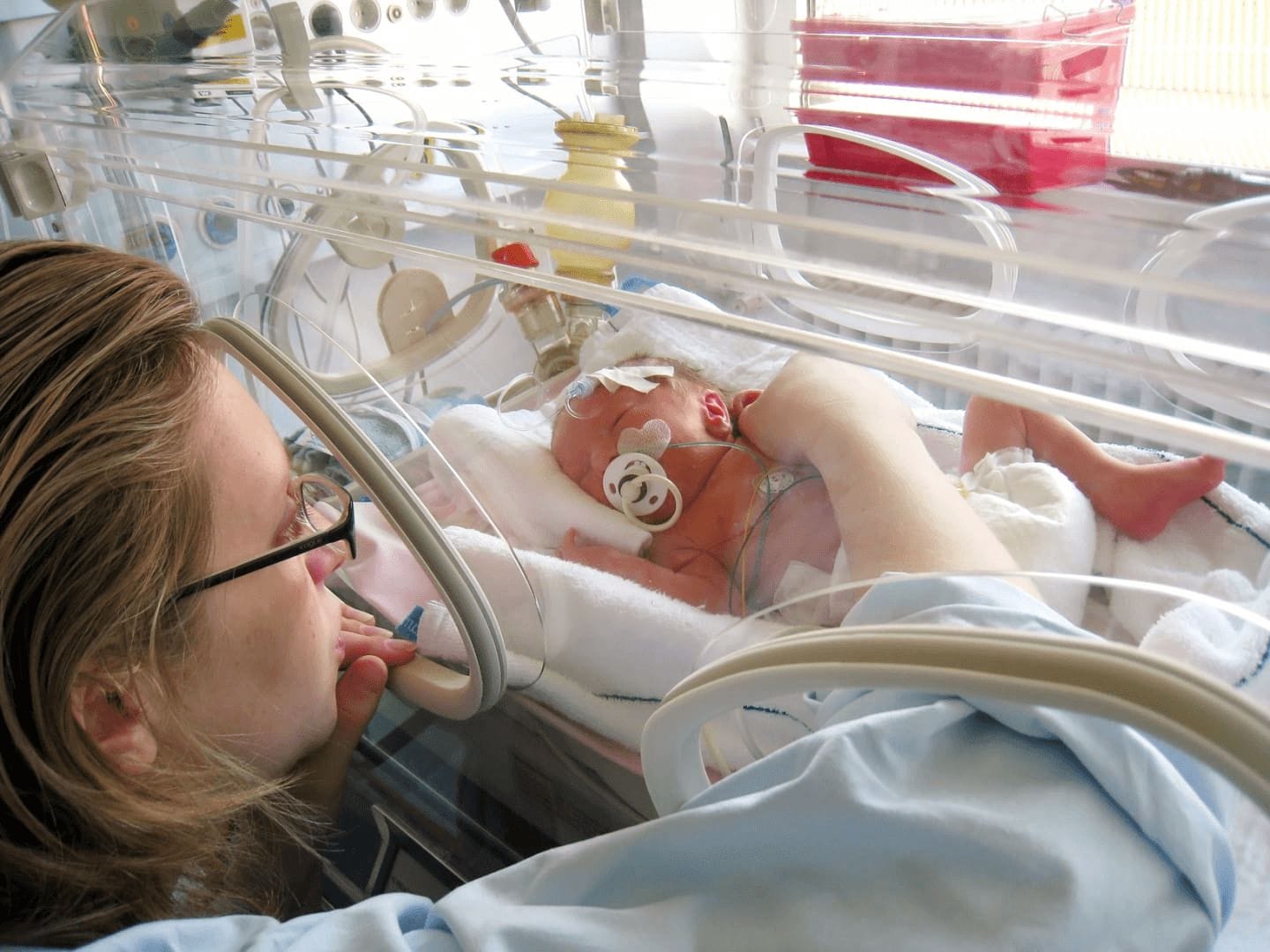 Dear NICU mama: Your strength is profound–and unexpected mom gently touching a baby in a NICU bed