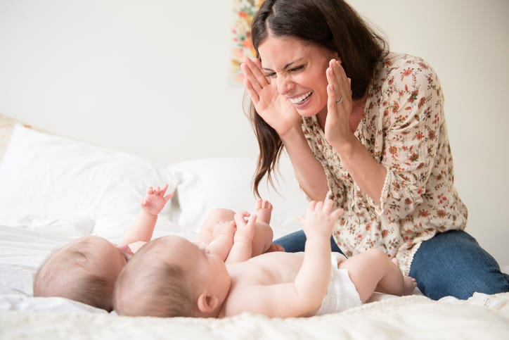 5 easy games to boost your baby’s development—and have fun too mom sitting in front of her babies playing peek-a-boo, one of the best baby development games