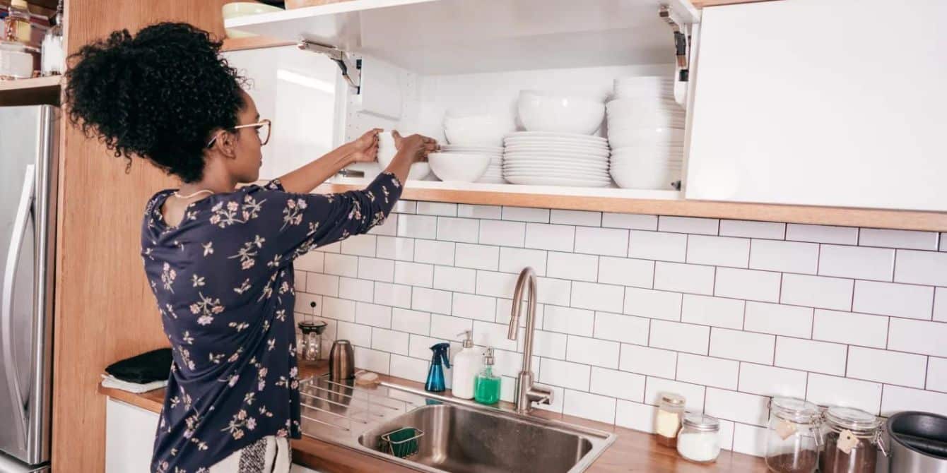 12 simple ways to organize your home for fall, now woman putting plates away- how to organize your home
