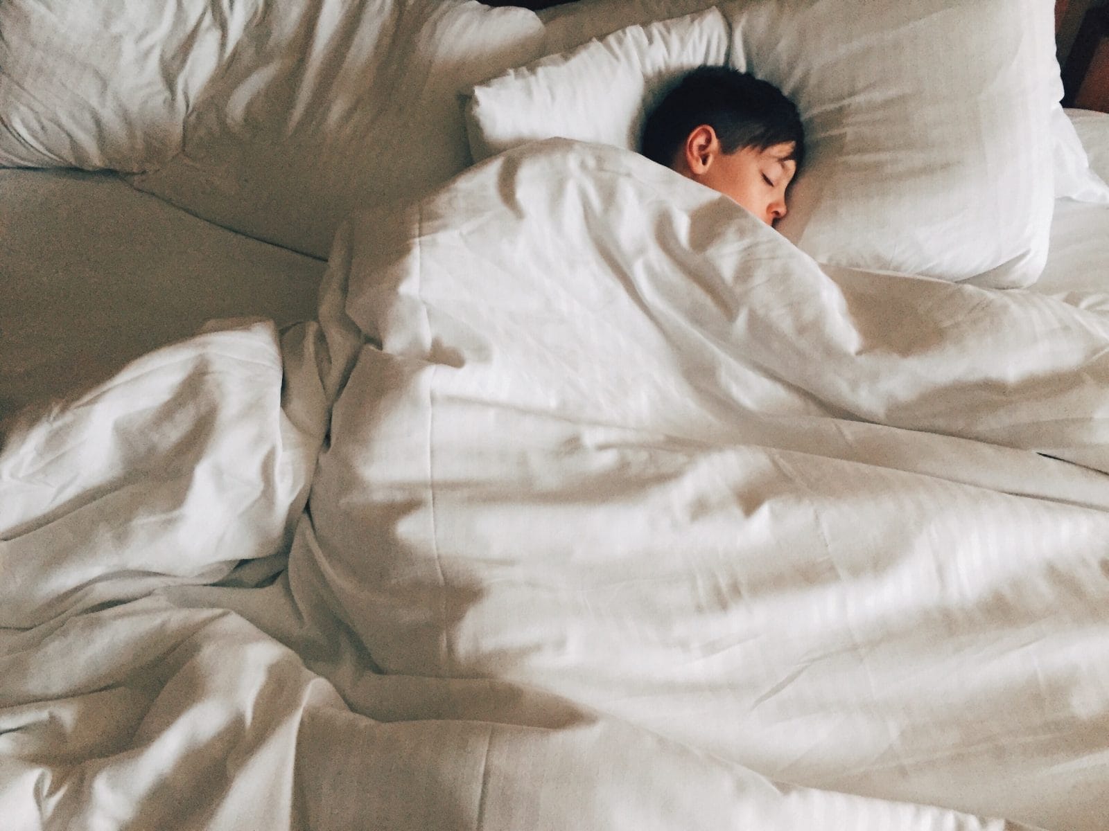 How to make sure your kids get enough sleep during the busy holiday season a child sleeping in a bed