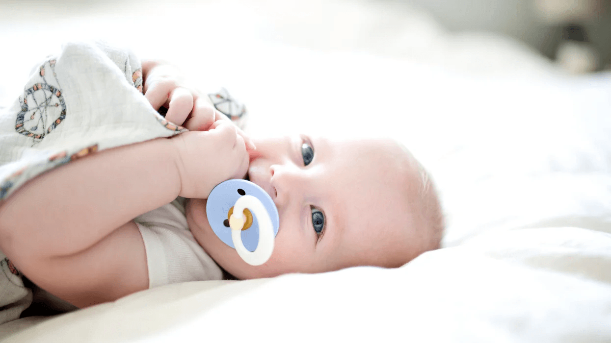 Why ‘cleaning’ a dropped pacifier with your own mouth might benefit baby baby laying on its back with a pacifier