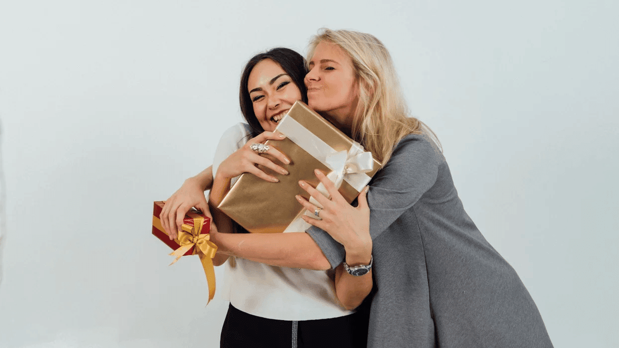 How to not go broke this holiday season two women hugging while holding wrapped presents
