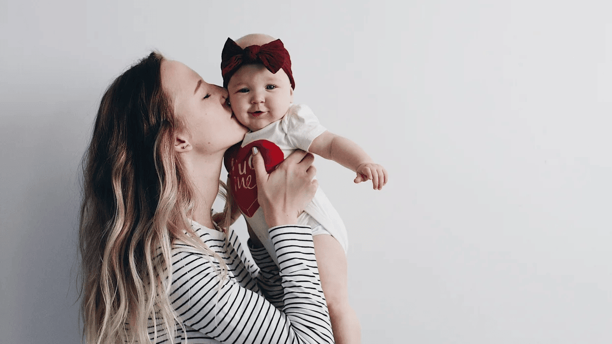 No, having a baby didn’t ‘ruin’ my 20s mom kissing baby girl on the cheek