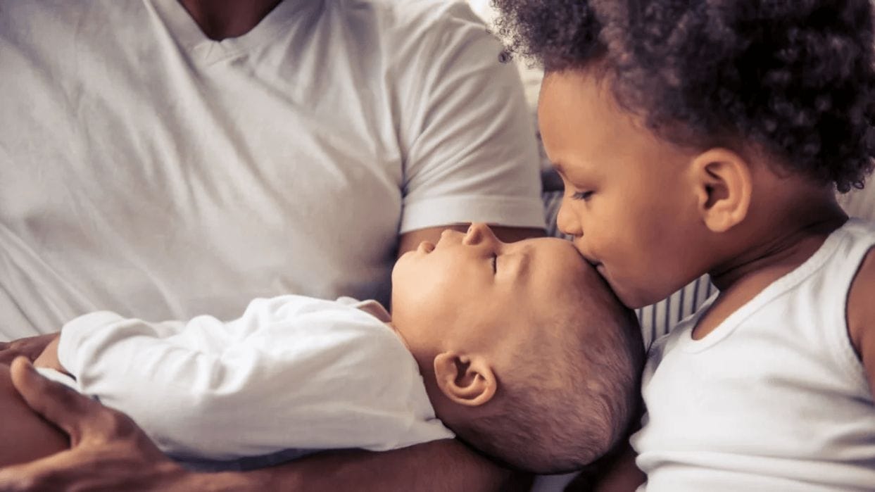 How to prepare your firstborn for bringing home baby #2 older child kissing newborn on the head