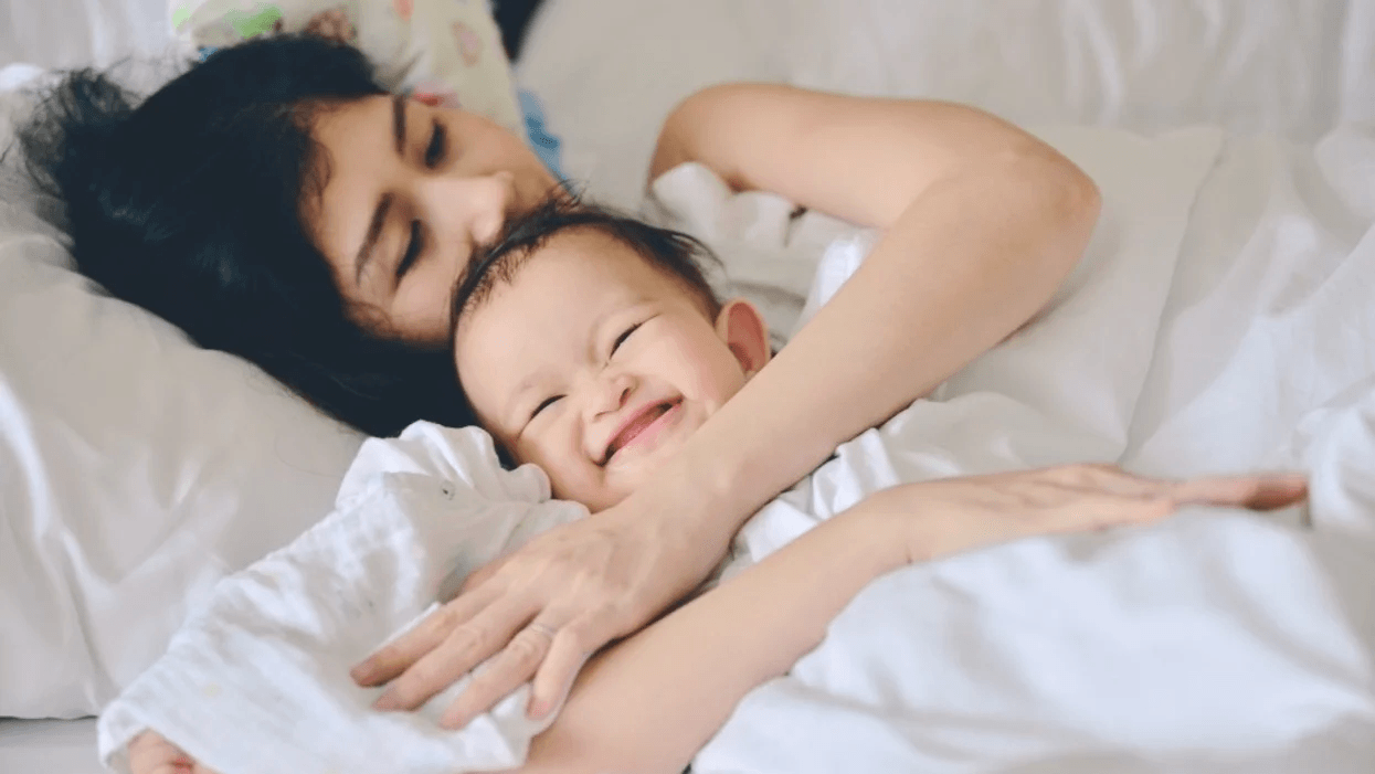 Single moms are raising awesome kids—and research confirms it mom hugging a smiley baby in bed