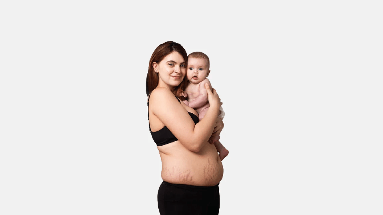 These viral photos from a UK ad campaign celebrate postpartum bodies–and we’re here for it mom wearing only bra holding new baby