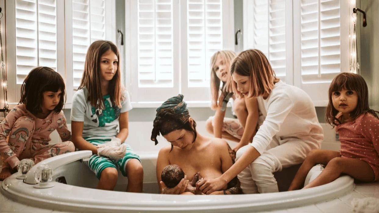 These viral photos of a mom’s home birth surrounded by her 5 daughters will leave you in awe mom holding a newborn after a homebirth surrounded by her 5 kids