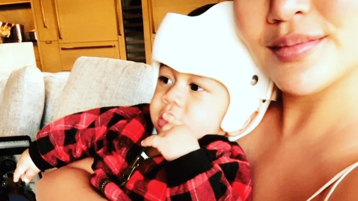 selfie of chrissy tiegen hold her son wearing a helmet