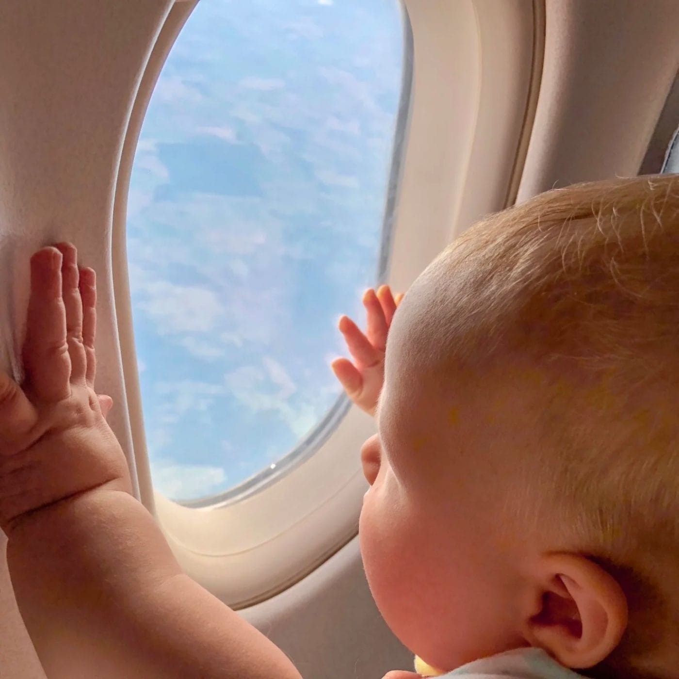 Flying with baby? 11 tips to make air travel with kids a breeze baby with their hands on airplane window