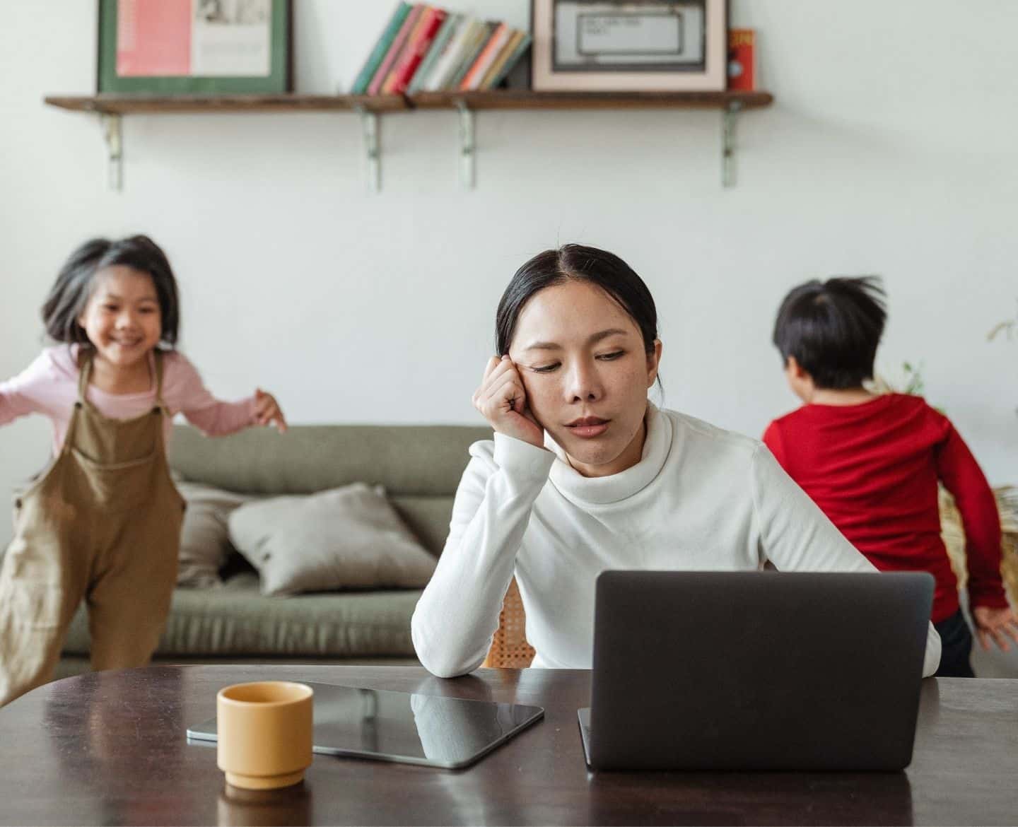 I’m so ready for school to start annoyed mama on a computer while kids play behind her