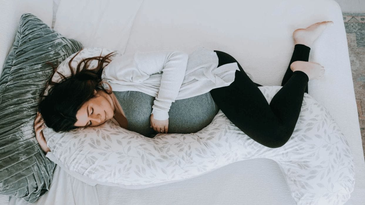 Introducing: The Esse Pregnancy Support Pillow—for every stage and need of pregnancy & postpartum pregnant woman laying with a pregnancy pillow