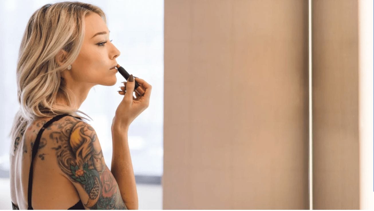 5 beauty tips to help you look (and feel) put together–even if you haven’t slept in months woman putting on lipstick in a mirror