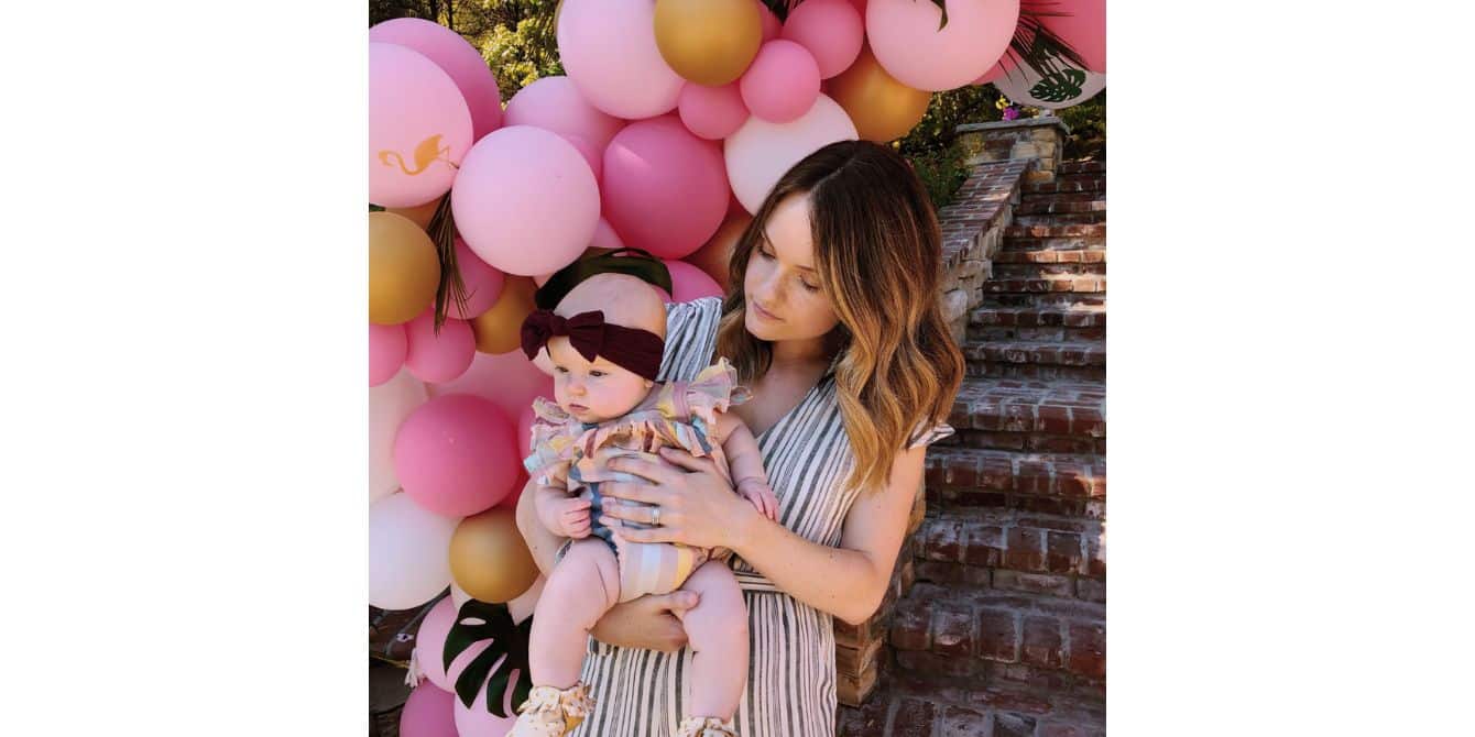 Angela on realizing her anxiety and sadness weren’t normal mom holding baby during first birthday party - essay on perinatal mood disorders