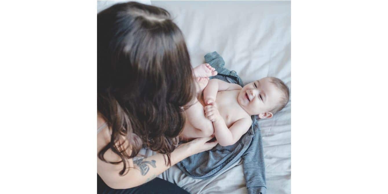 Bonnie on postpartum depression and sleep-training mom playing with baby on a bed - an essay on unsuccessful sleep training