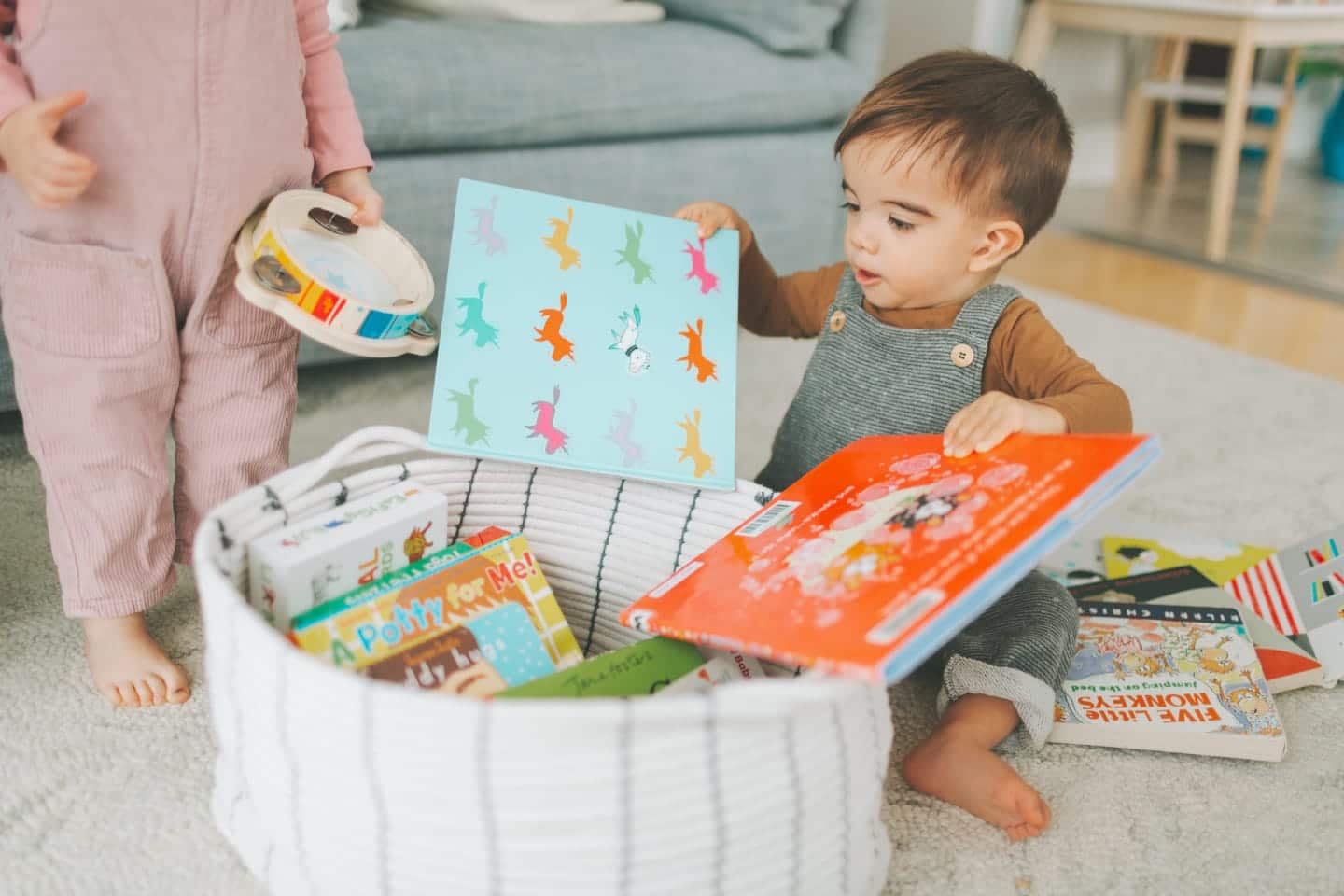 I re-organized our playroom to be Montessori-ish–and it made a huge difference littie boy grabbing books out of a basket