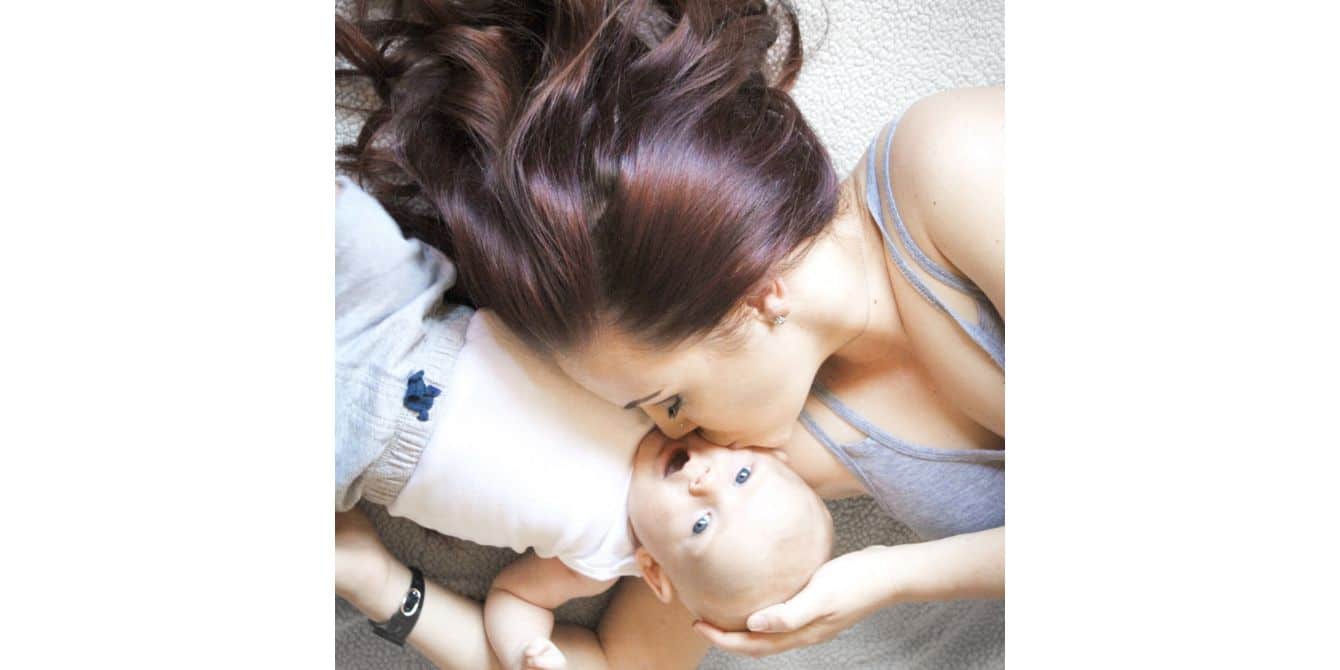 Toni on what she wants moms to know about postpartum depression mom kissing her newborn son on the cheek while they both lay on the floor
