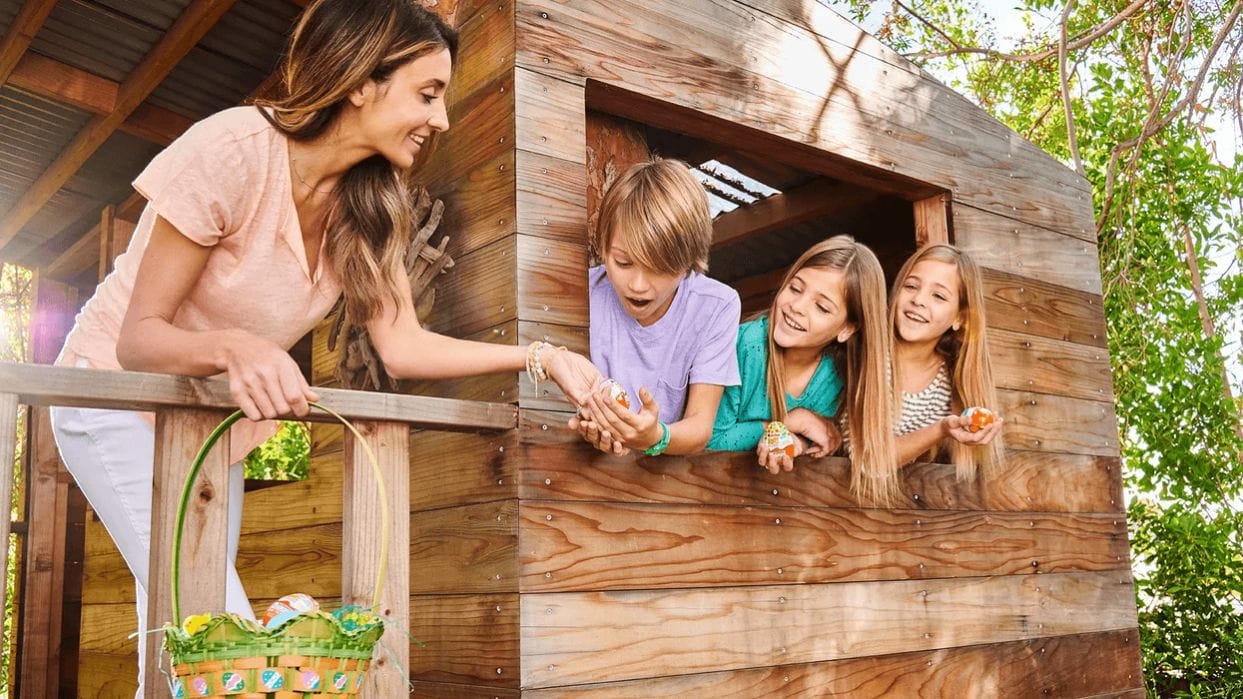 Last-minute Easter basket inspiration for busy mamas mom giving chocolate eggs to kids in a treehouse