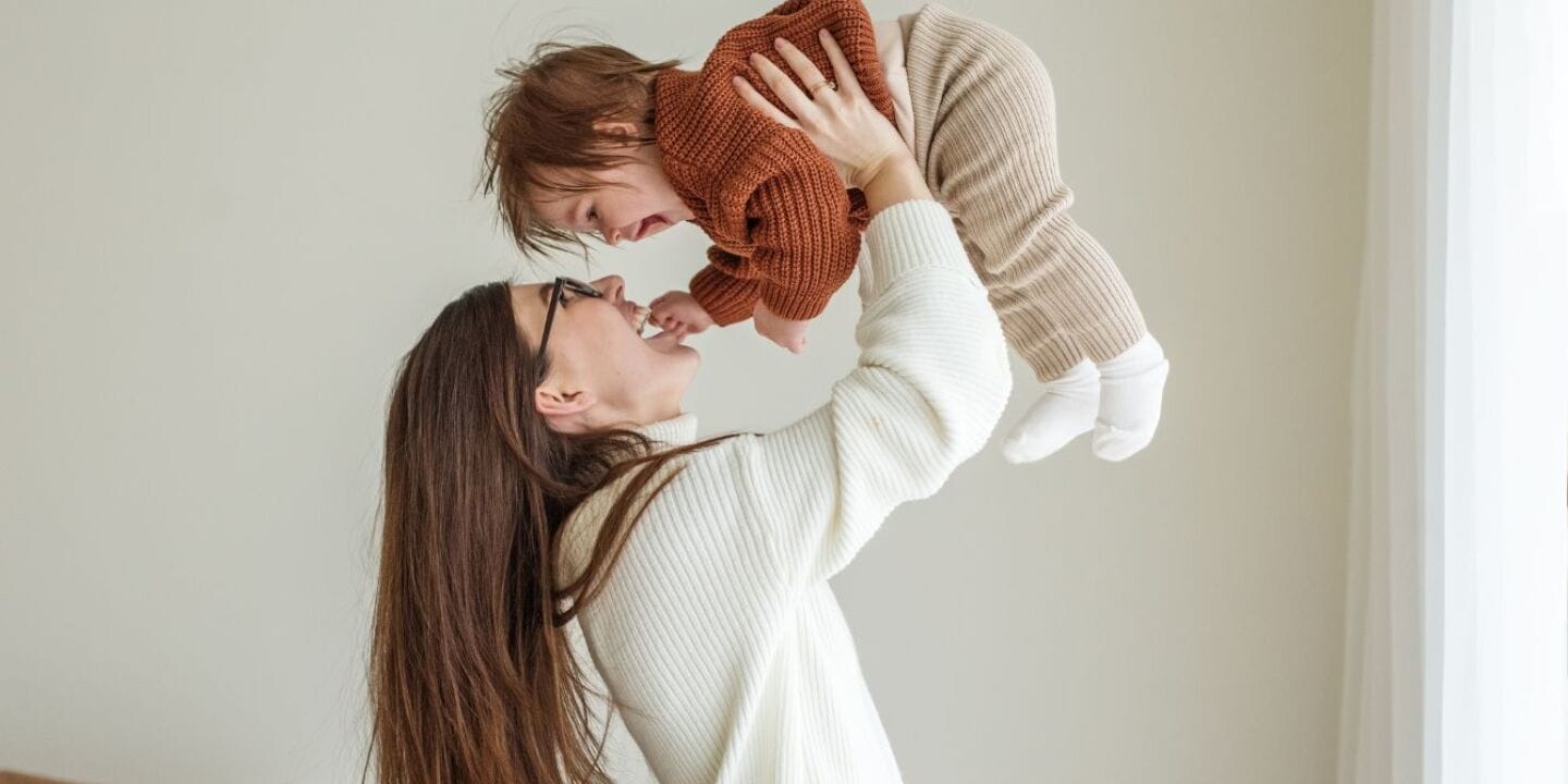 woman holds baby boy in the air - popular baby boy names