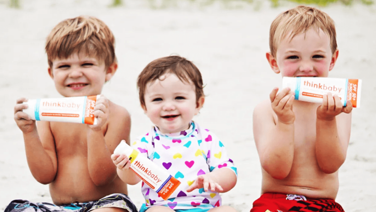 The EWG just gave this non-toxic sunscreen a perfect safety score 🙌 babies holding a tube of Thinkbaby sunscreen