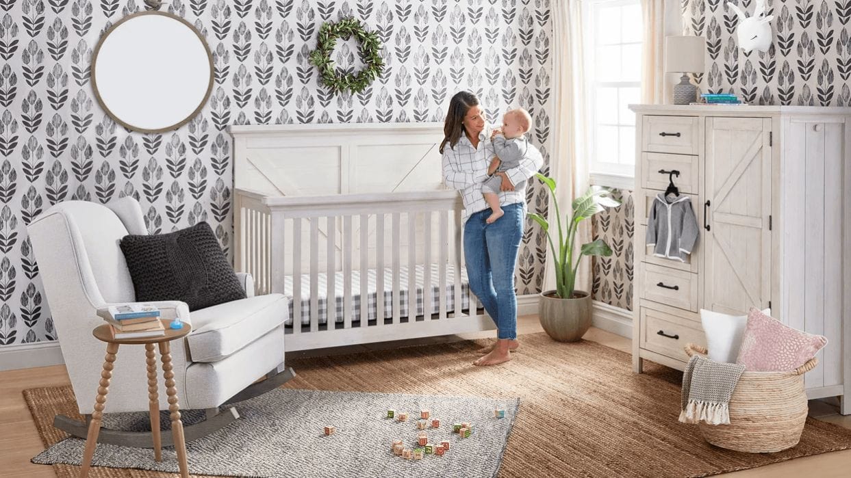 How to design a nursery that can last through toddler years + beyond mom holding a baby outside of his crib