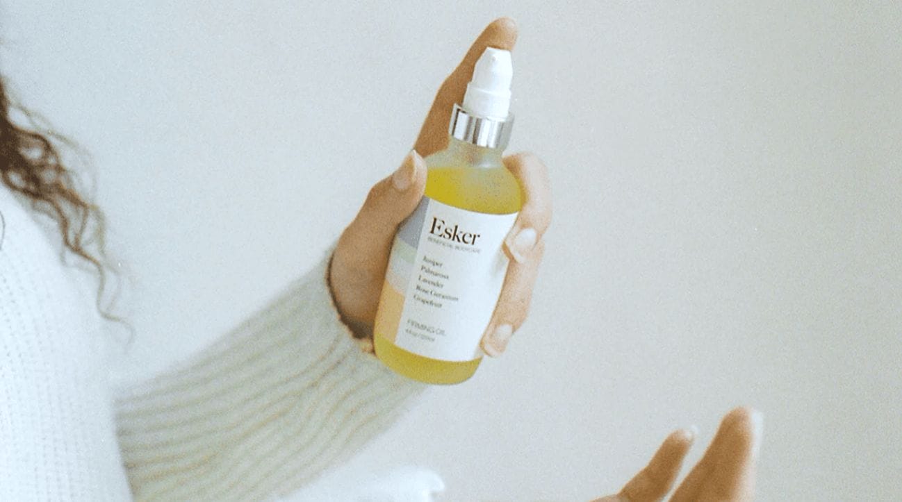This oil completely changed my skin this summer woman holding bottle of Esker face oil