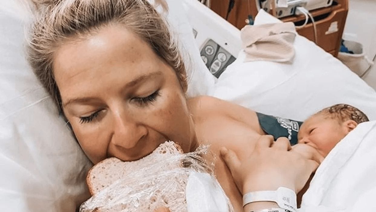 The scientific reason why that first post-birth meal tastes SO good mom taking a bite of deli sandwich while baby breastfeeds after giving birth
