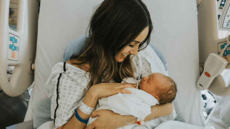 10 newborn photo ideas that you’ll cherish forever mom holding her new baby in the hospital, one of motherly's favorite newborn photo ideas