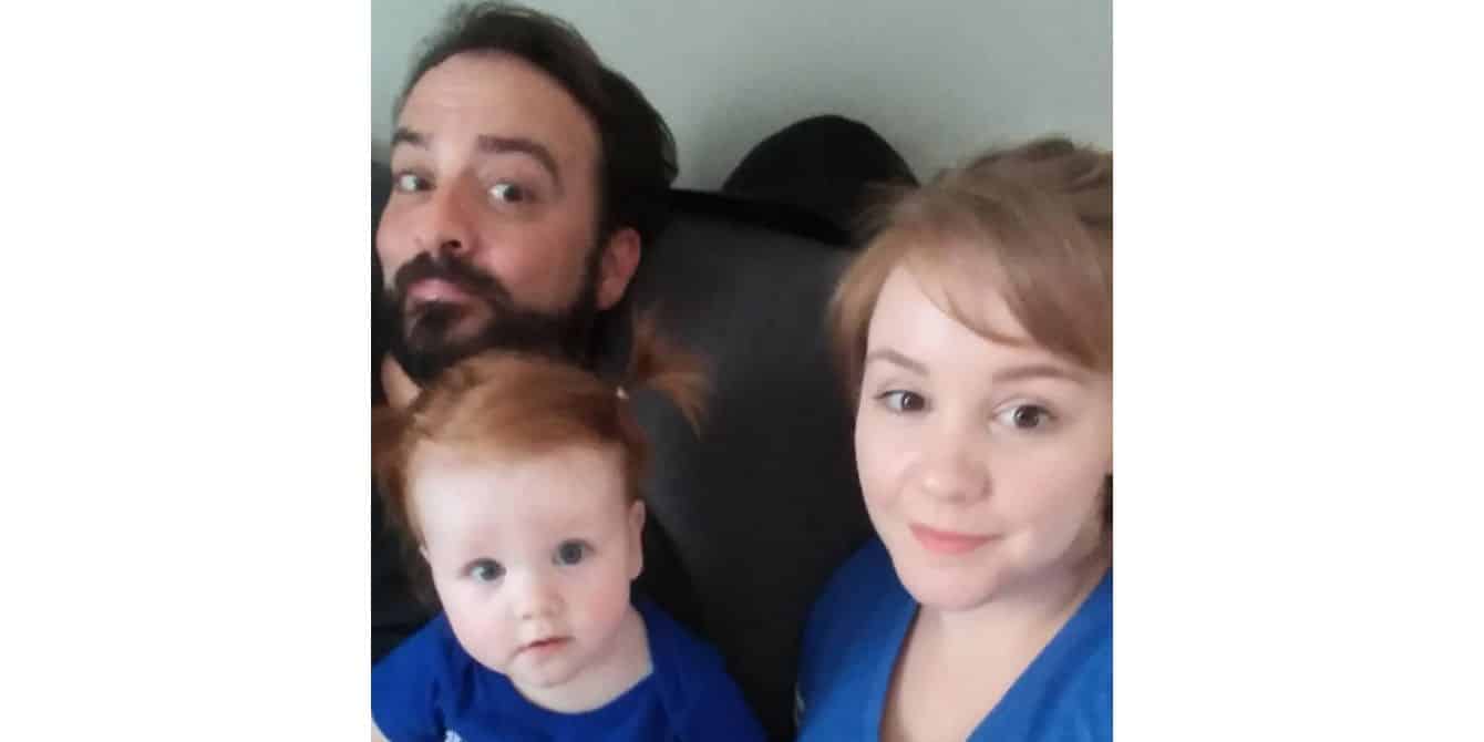 Kelly on having to go to prenatal appointments alone because of Covid-19 restrictions family selfie with mom, dad and toddler son sitting on the couch - essay on pregnancy during Covid-19