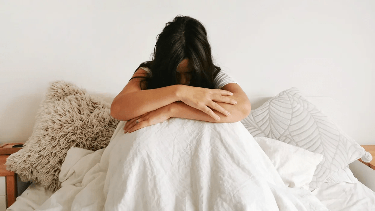A love letter to the mama struggling to get through this pandemic mom hugging knees sitting in bed