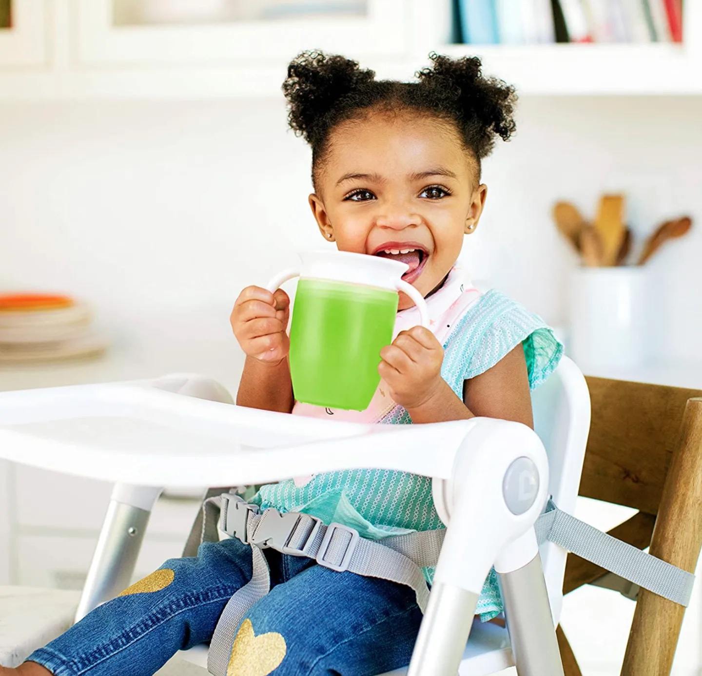 10 sippy cups that your kids will actually want to drink from little girl drinking from a sippy cup in her high chair