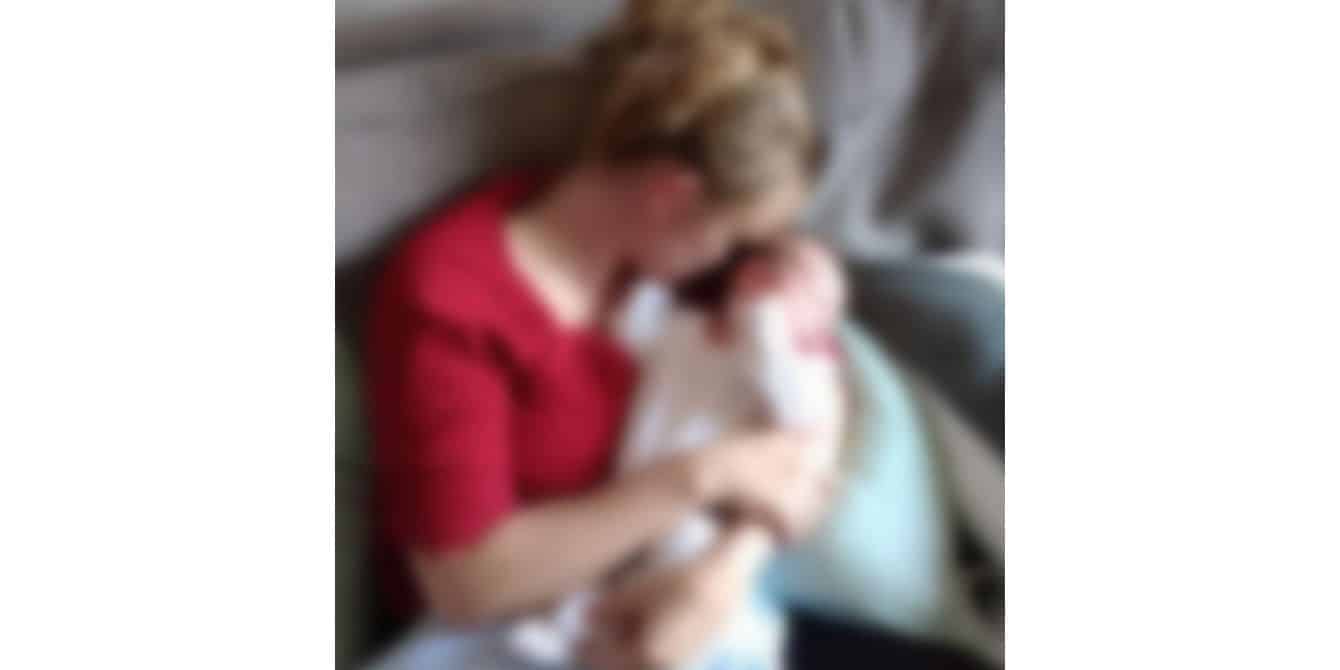 Olivia on taking care of a baby while dealing with her husband’s postpartum depression blurry image of a mom holding her baby - essay on husband's postpartum depression