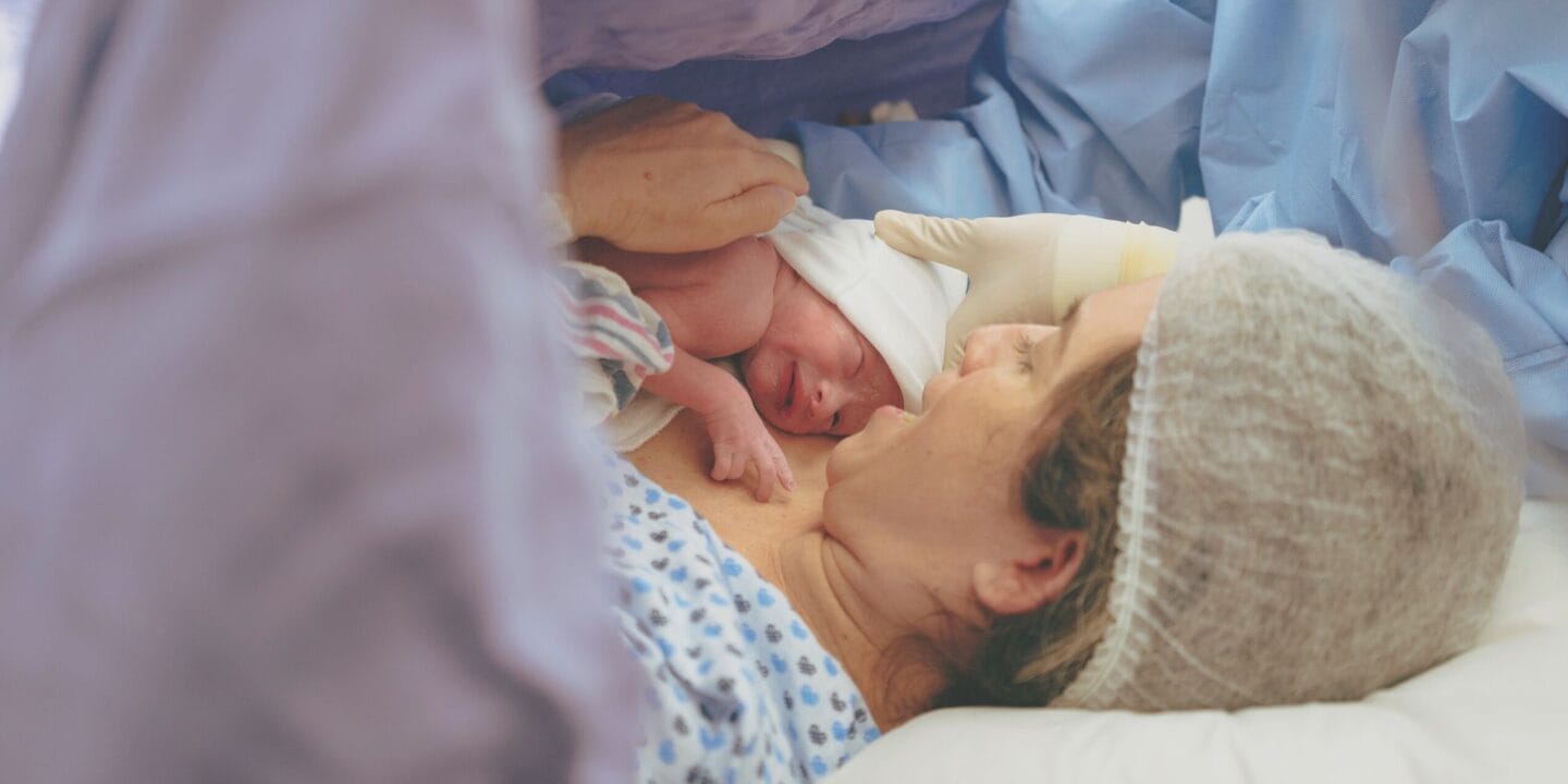 What happens during a C-section? A midwife answers your FAQs Mother holding infant after c-section birth showing what happens during a c-section delivery