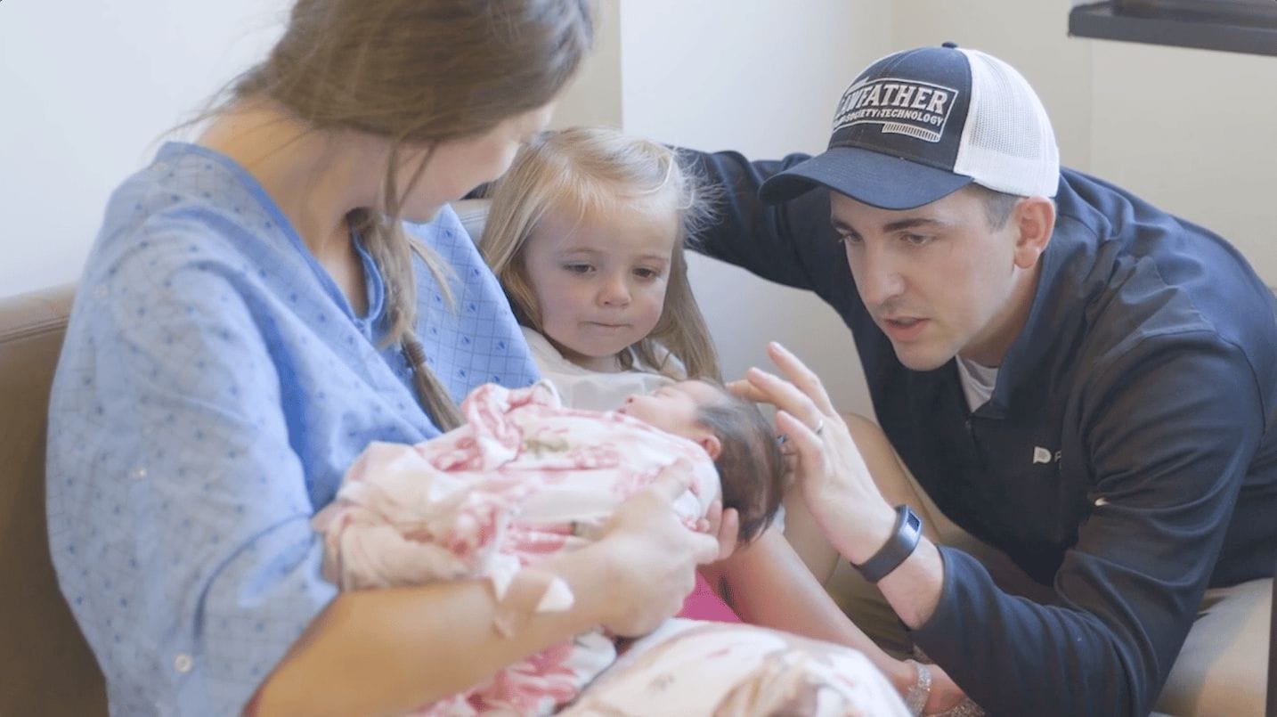This is birth: A girl mom story mom holding a newborn baby while dad and toddler look