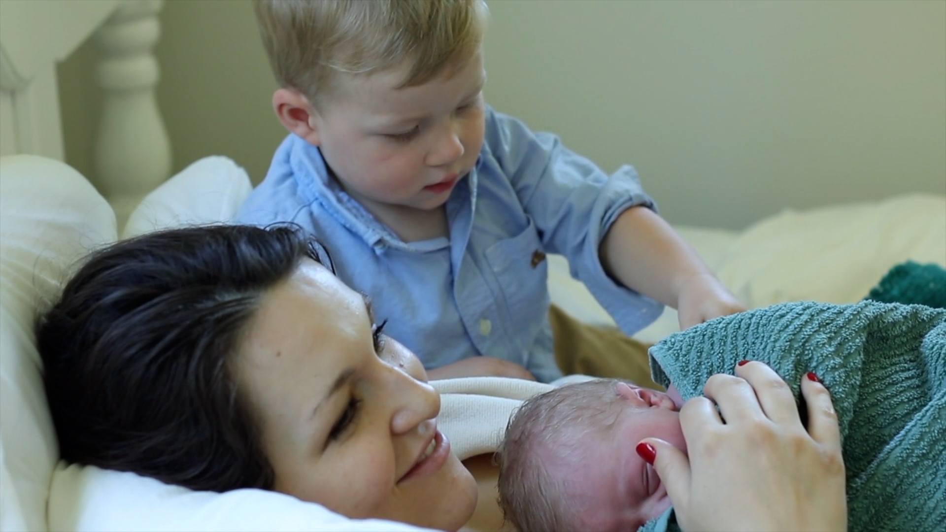 This is birth: A home waterbirth story mom holding newborn son while older son stands behind her