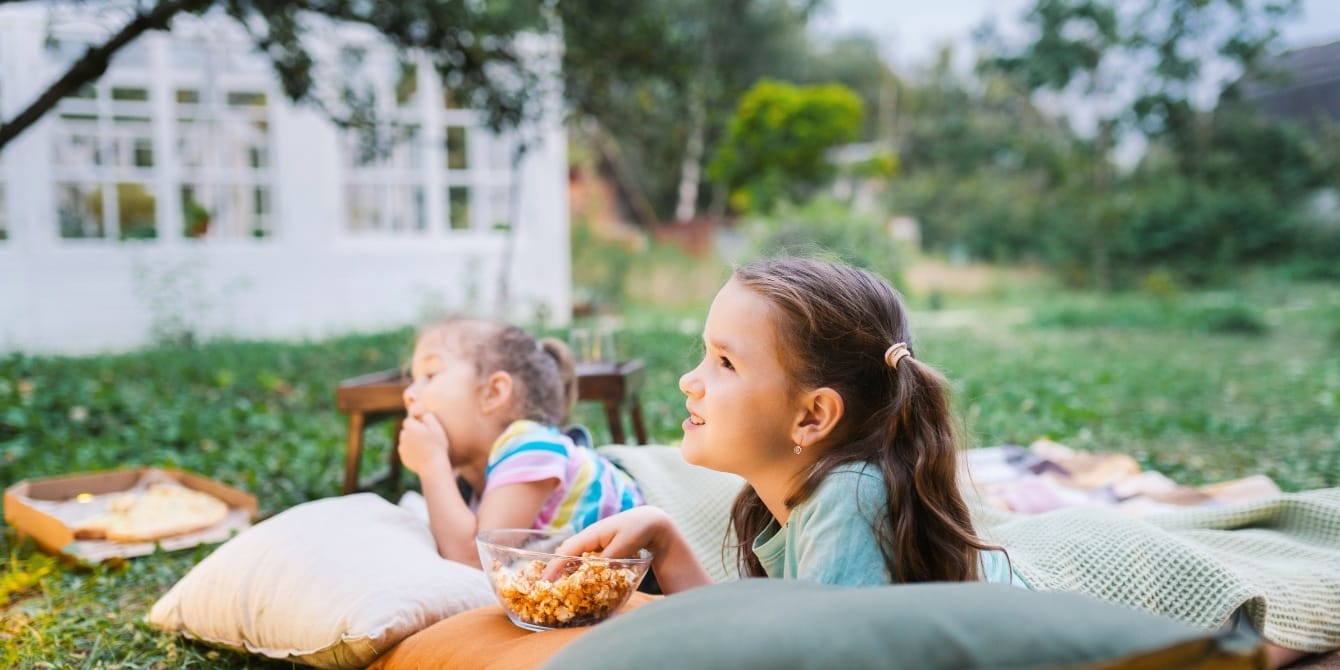 Everything you need for an outdoor movie night little girls watching a movie for outdoor movie night, a perfect summer activity- how to host an outdoor movie night