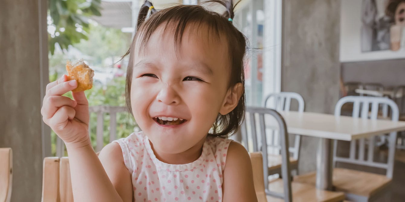 7 delicious Super Bowl snack recipes that even your toddler will devour little girl eating nuggets- super bowl snack recipes