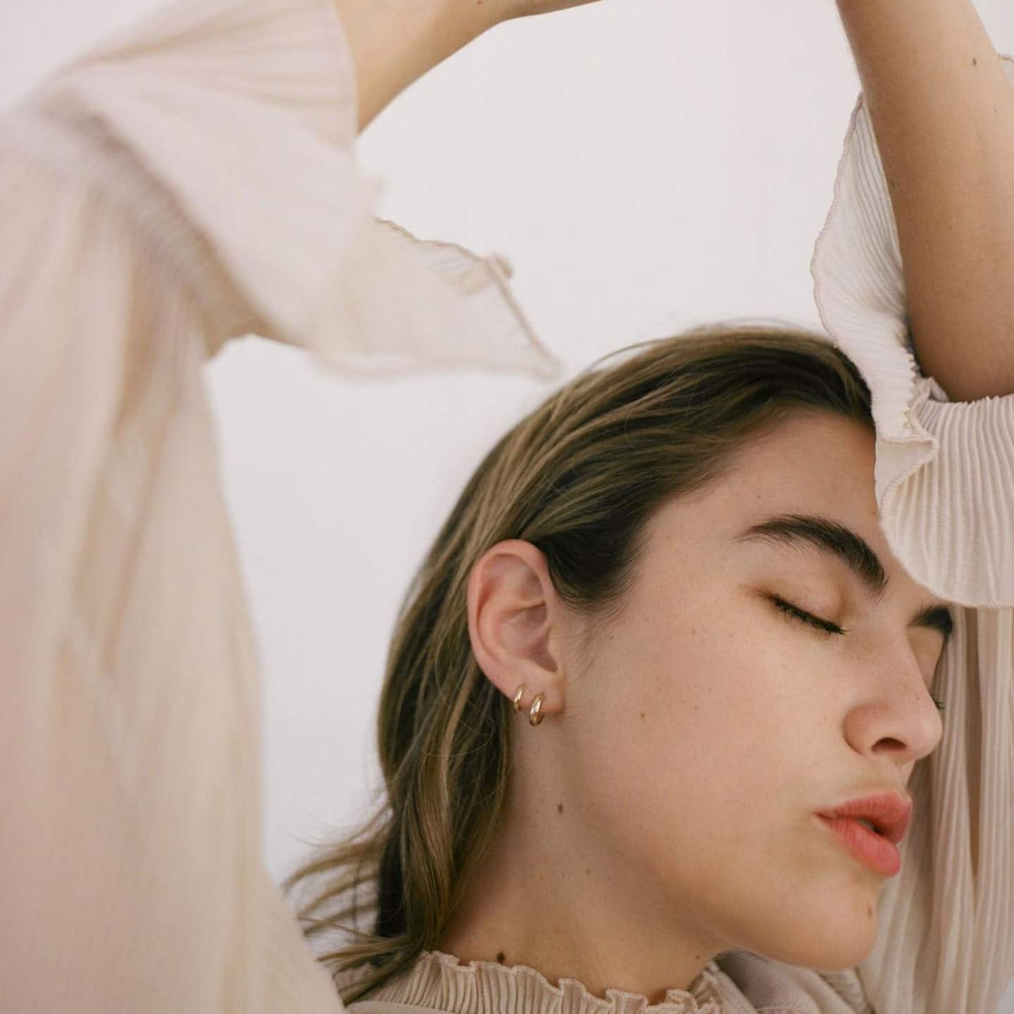 11 mama-friendly huggie earrings you can wear 24/7 woman wearing gold hoop earrings