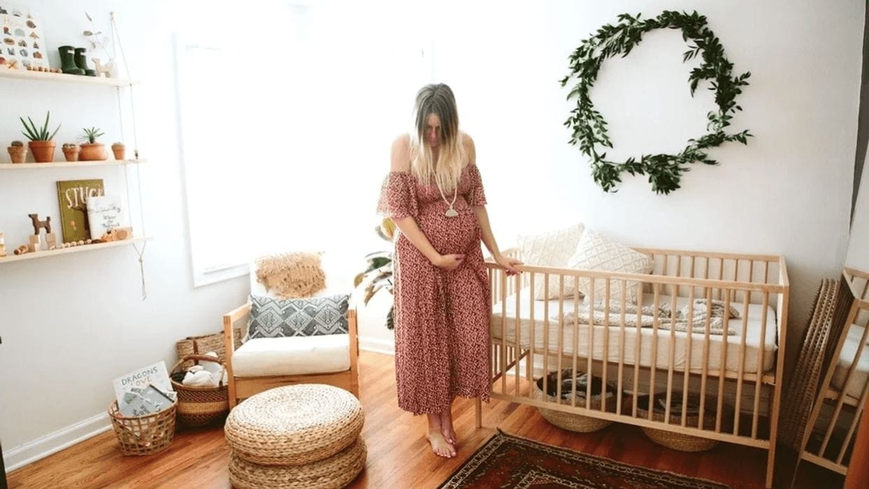 Trending now: Greenery in your baby’s room woman holding her belly standing in a nursery