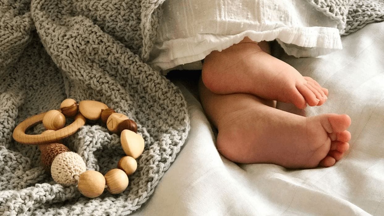 How to create a Montessori-inspired baby registry baby feet next to a montessori toy