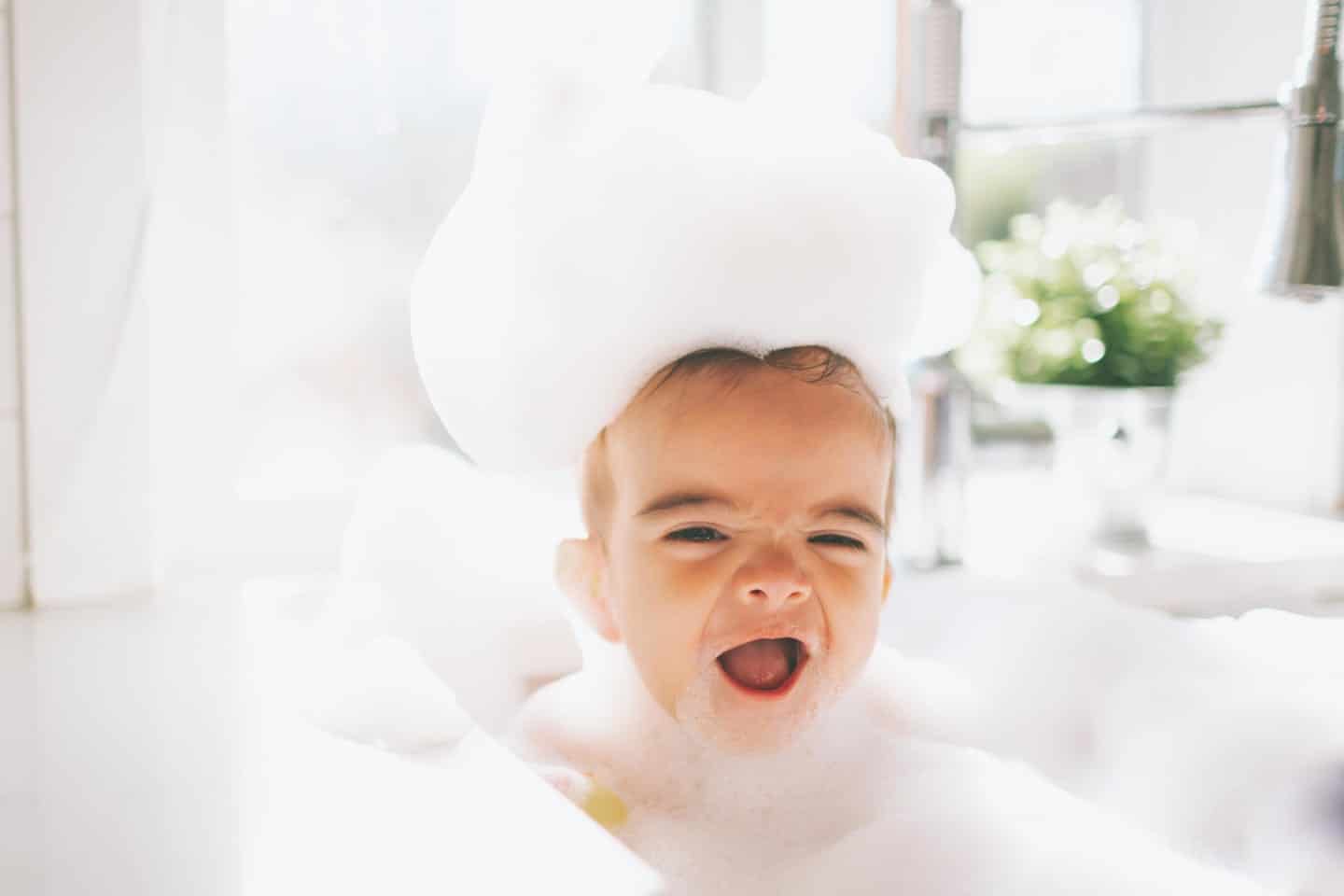 8 Montessori-inspired bath toys that turn bath time into a learning experience baby in a bubble bath, getting ready to play with montessori bath toys